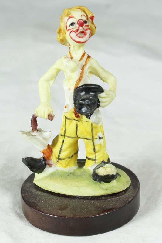 Clown with umbrella on wooden stand
