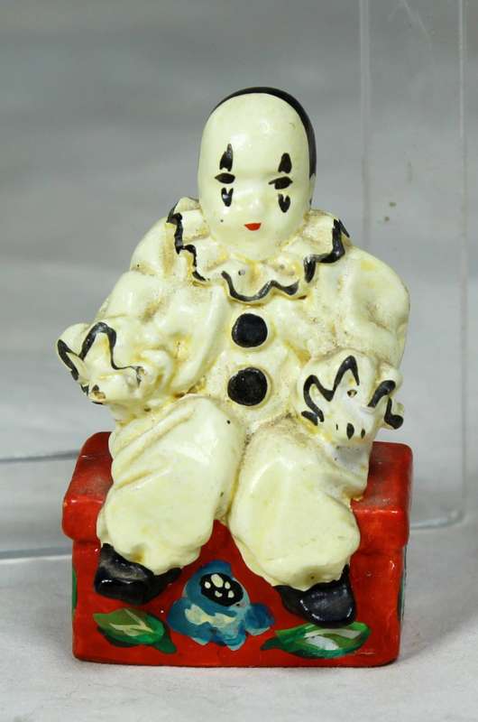 Miniature clown sitting on a chest