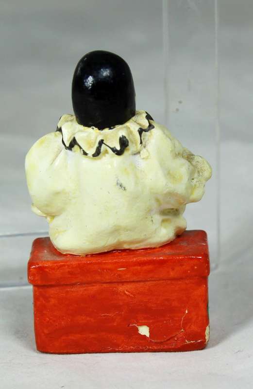 Miniature clown sitting on a chest