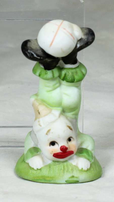 Small clown doing a handstand with a ball