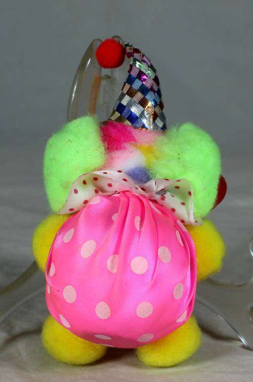 Fuzzy clown dressed in pink holding a good luck sign