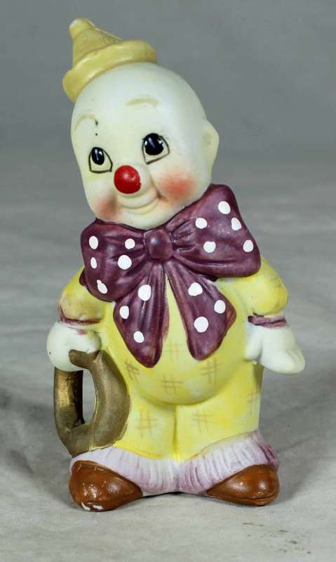 Ceramic clown in a brown bowtie carrying a ring