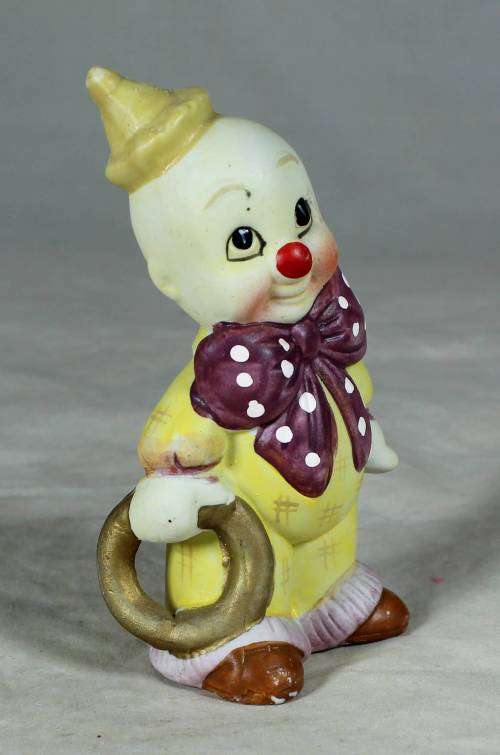 Ceramic clown in a brown bowtie carrying a ring