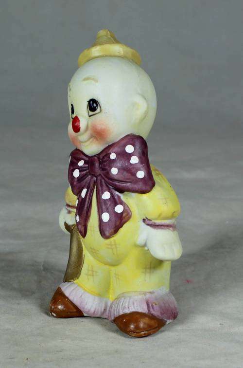 Ceramic clown in a brown bowtie carrying a ring