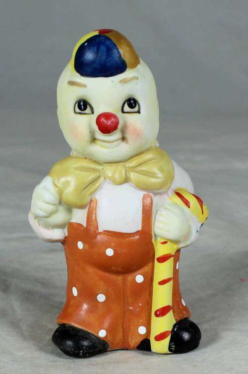 Ceramic clown in an orange jump suite holding a candy cane
