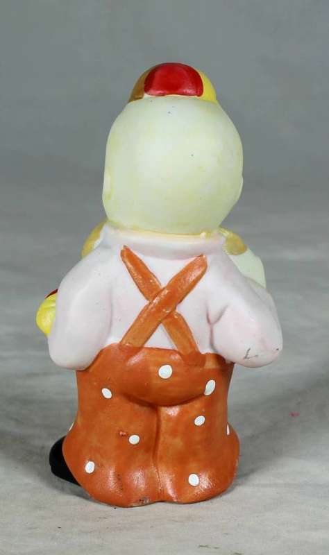 Ceramic clown in an orange jump suite holding a candy cane