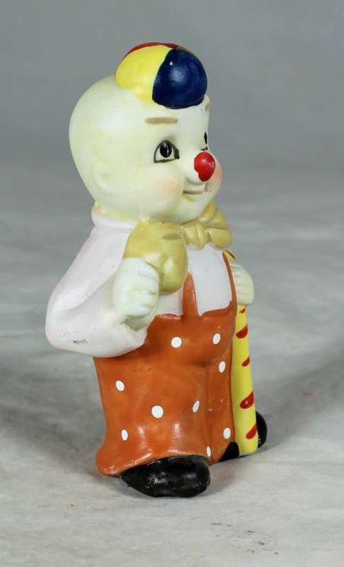 Ceramic clown in an orange jump suite holding a candy cane