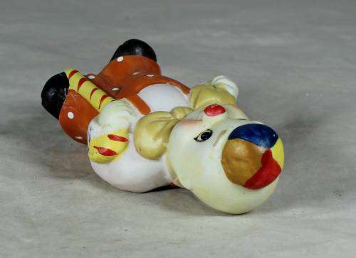 Ceramic clown in an orange jump suite holding a candy cane