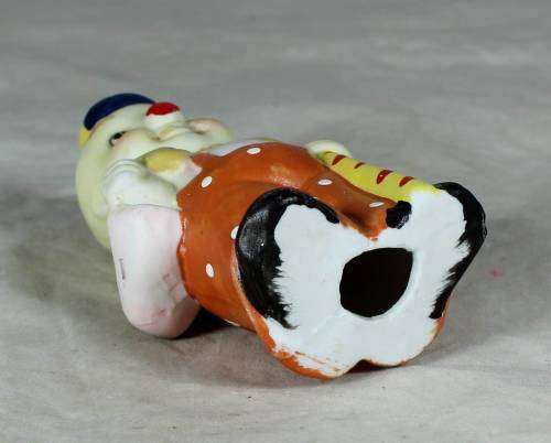 Ceramic clown in an orange jump suite holding a candy cane