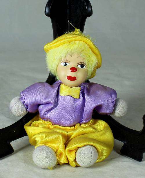 porcelain and cloth clown in a yellow hat and pants
