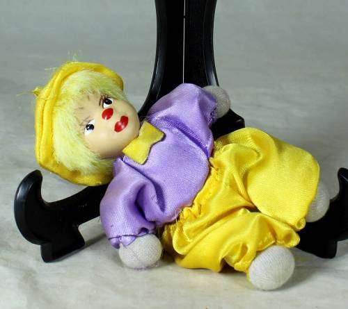 porcelain and cloth clown in a yellow hat and pants
