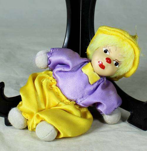 porcelain and cloth clown in a yellow hat and pants