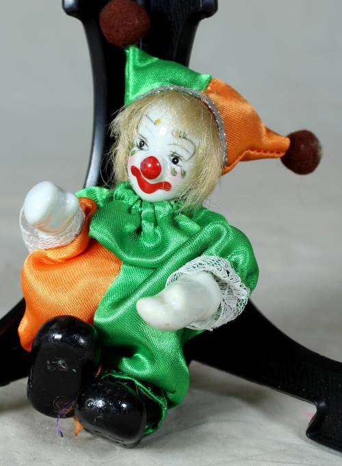 porcelain and cloth clown in a green and orange suit