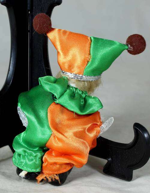 porcelain and cloth clown in a green and orange suit