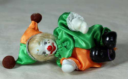 porcelain and cloth clown in a green and orange suit