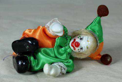 porcelain and cloth clown in a green and orange suit