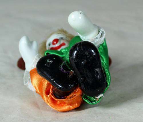 porcelain and cloth clown in a green and orange suit