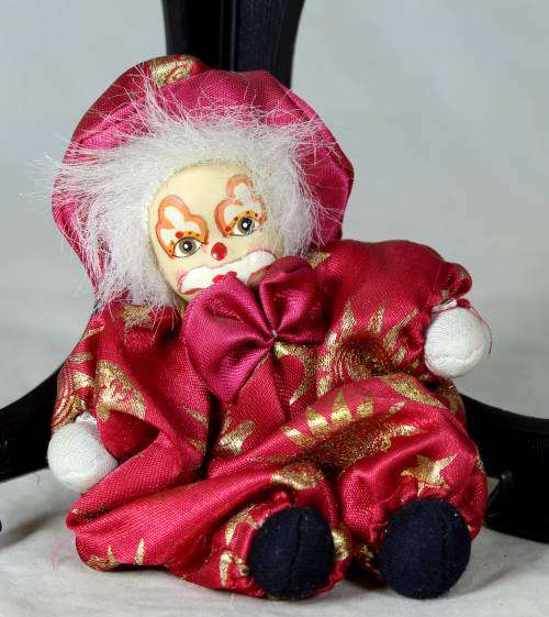 porcelain and cloth clown dressed in a red jump suit