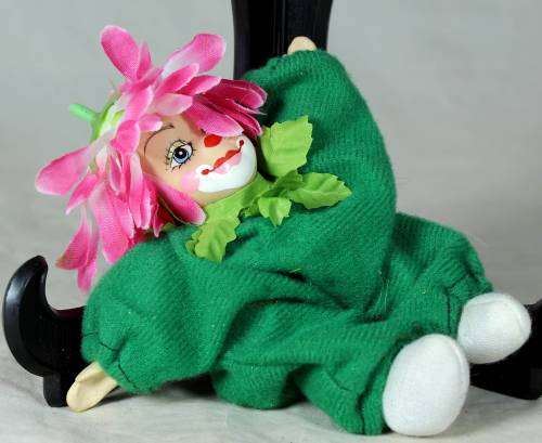 porcelain and cloth clown dressed in a green jump suit