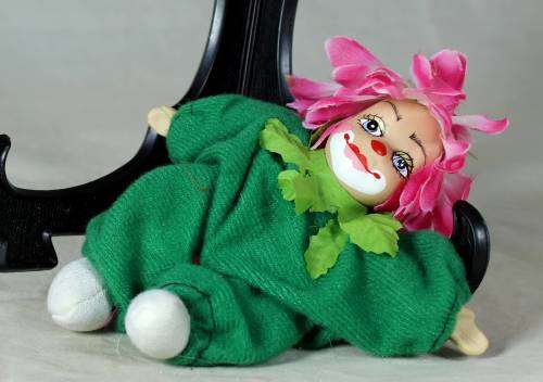 porcelain and cloth clown dressed in a green jump suit