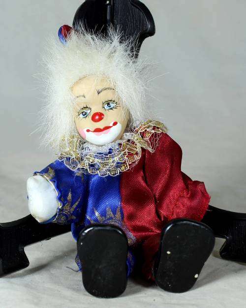 Porcelain and cloth clown dressed in a blue and purple jump suit
