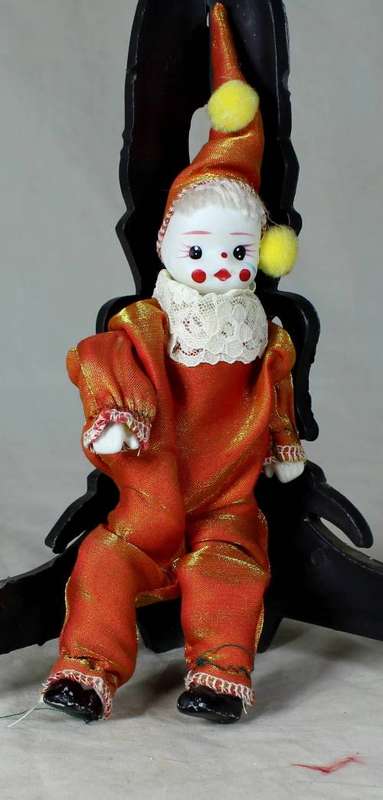 PORCERLAIN AND CLOTH CLOWN DRESSED IN A ORANGE JUMP SUIT