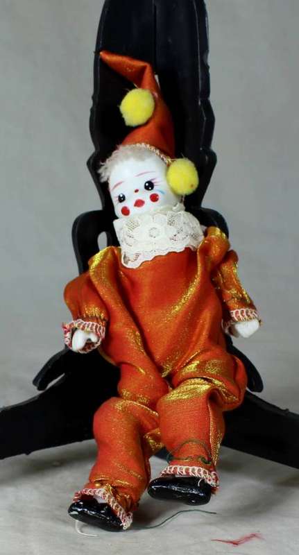 PORCERLAIN AND CLOTH CLOWN DRESSED IN A ORANGE JUMP SUIT
