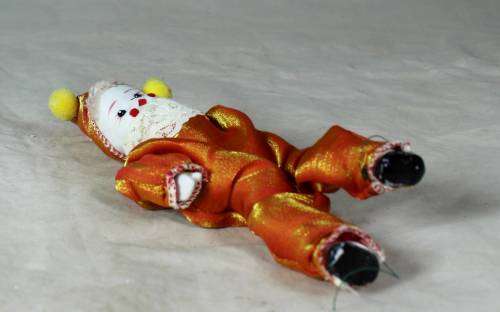 PORCERLAIN AND CLOTH CLOWN DRESSED IN A ORANGE JUMP SUIT
