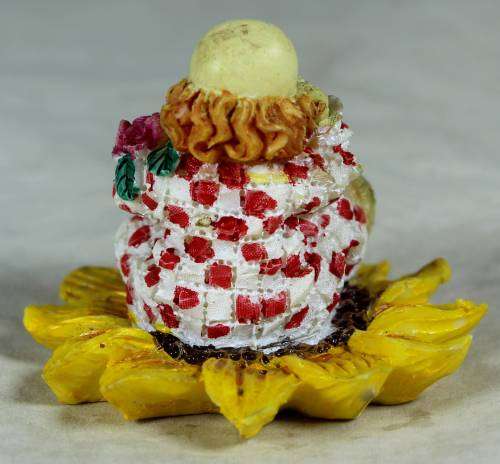 Ceramic clown sitting in a sunflower holding a bunch of roses