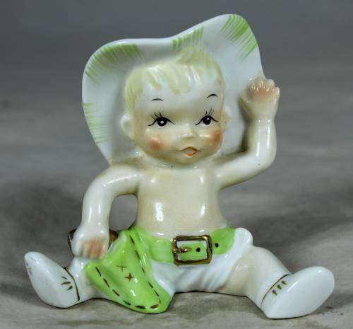 Porcelain sitting cowboy baby with a green gun belt