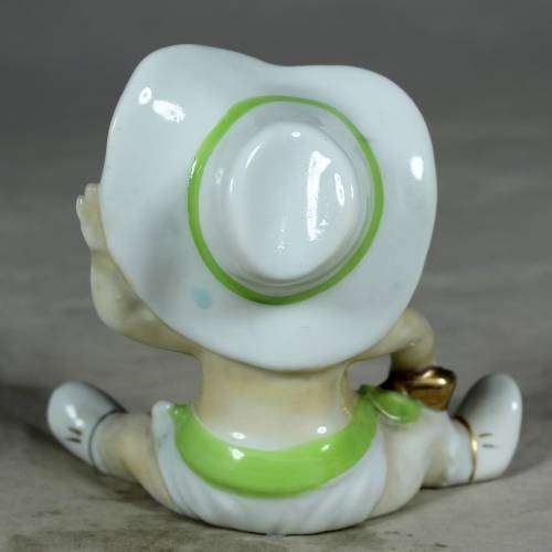 Porcelain sitting cowboy baby with a green gun belt