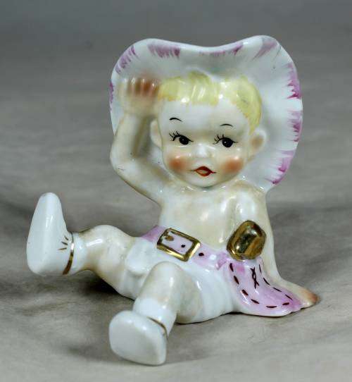 Porcelain sitting cowgirl with a pink gun belt