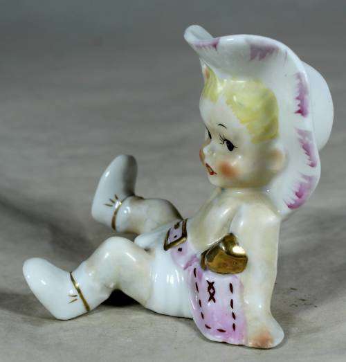 Porcelain sitting cowgirl with a pink gun belt