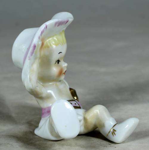 Porcelain sitting cowgirl with a pink gun belt