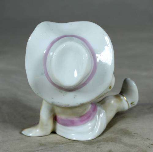 Porcelain sitting cowgirl with a pink gun belt
