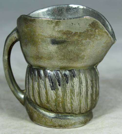 Small metal jug with a face