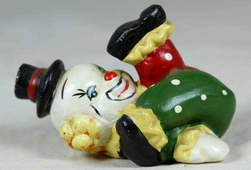 Miniature clown on his back with his foot in the air