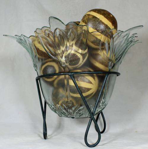 Large glass center piece on a metal stand with large round seed balls