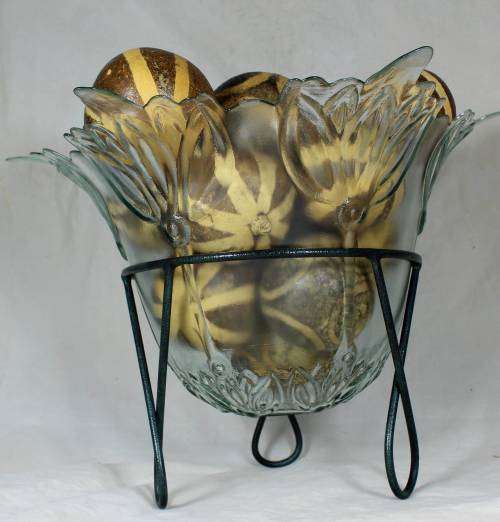 Large glass center piece on a metal stand with large round seed balls
