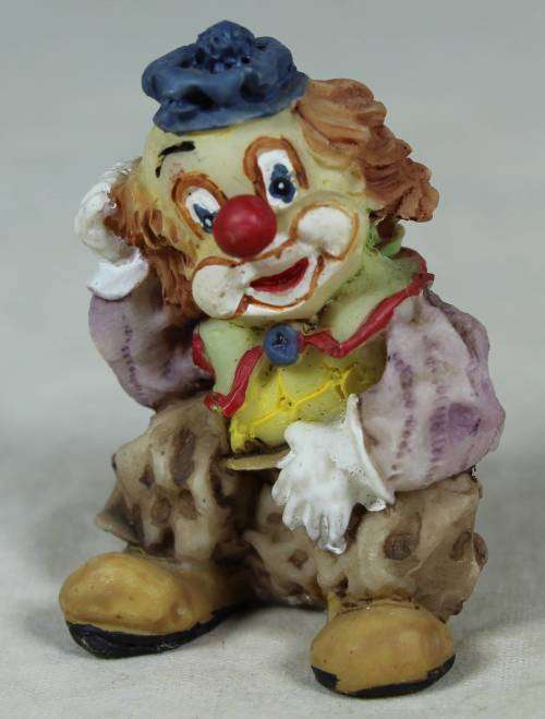 Miniature clown seated scratching his head