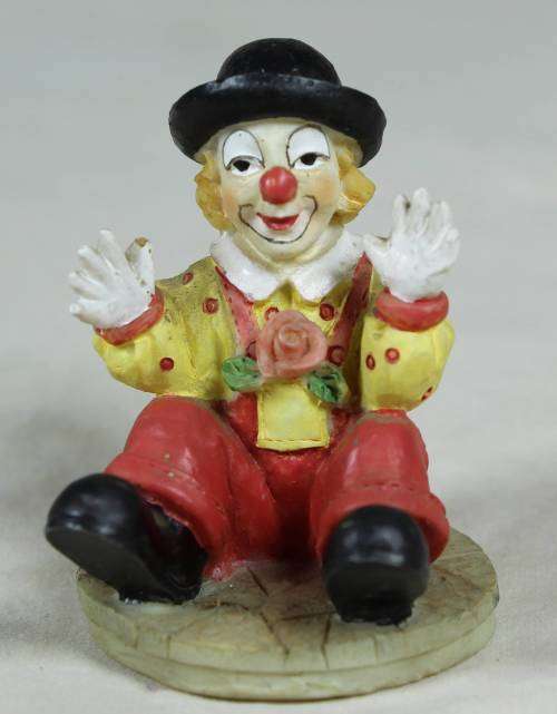 Miniature seated clown with raised hands
