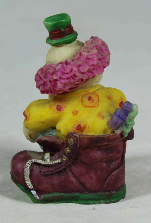 Miniature clown sitting in a shoe polishing his shoe
