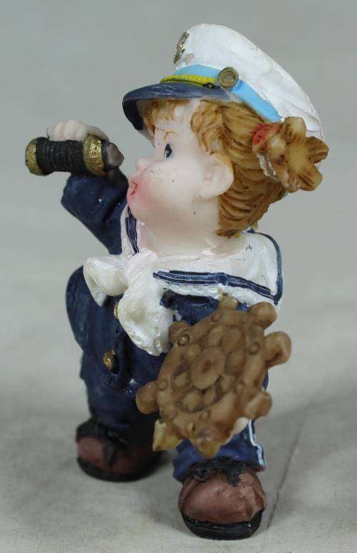 Kid sailor in blue holding a telescope and ships wheel