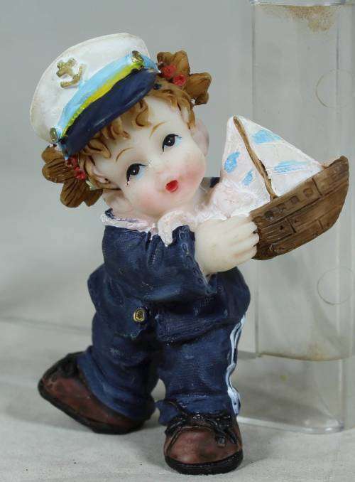 Kid sailor in blue holding a sail boat