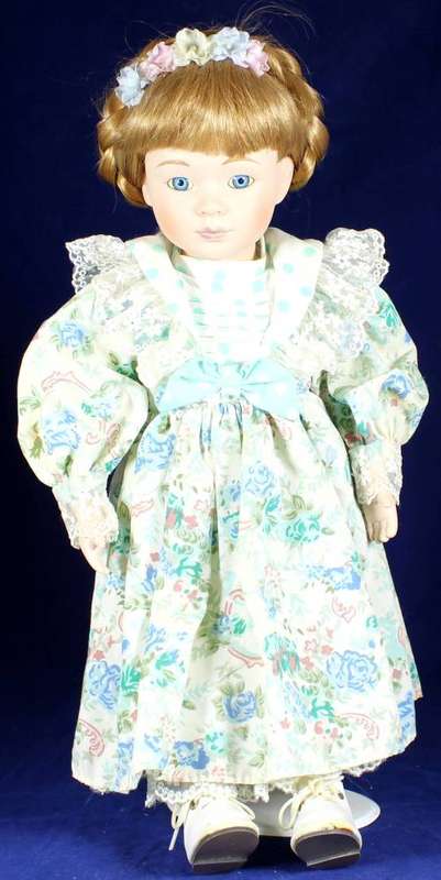 Porcelain doll girl in floral green dress on stand
