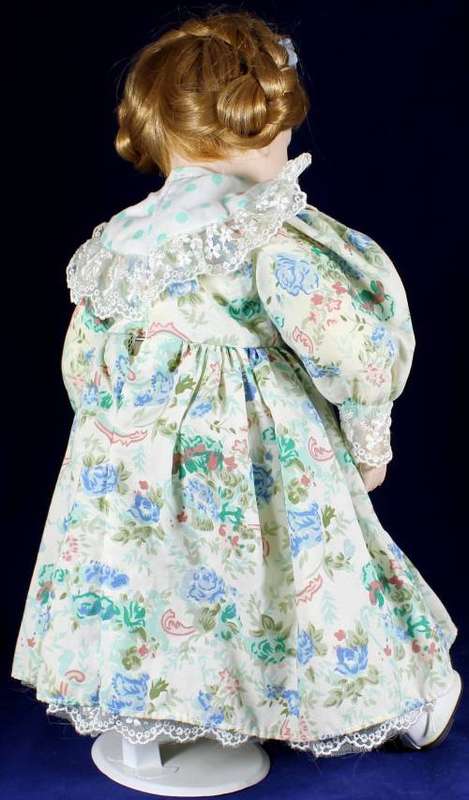 Porcelain doll girl in floral green dress on stand