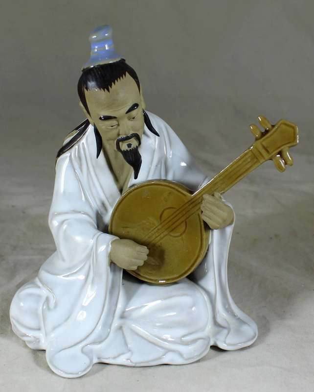 Mud man sitting with guitar