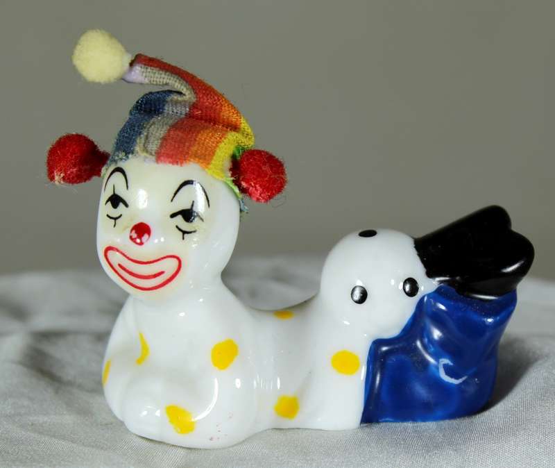 Clown laying on stomach with ball behind legs