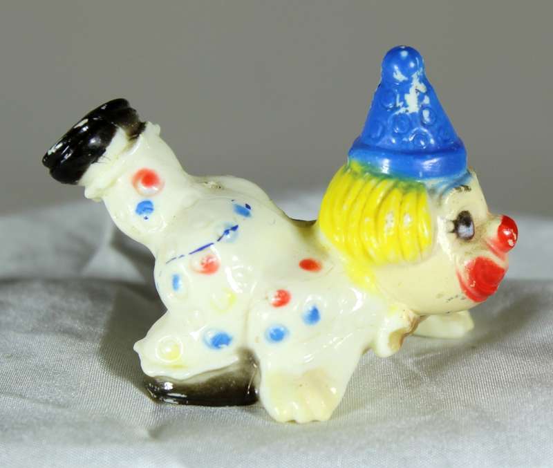 Miniature clown on stomach with leg in the air