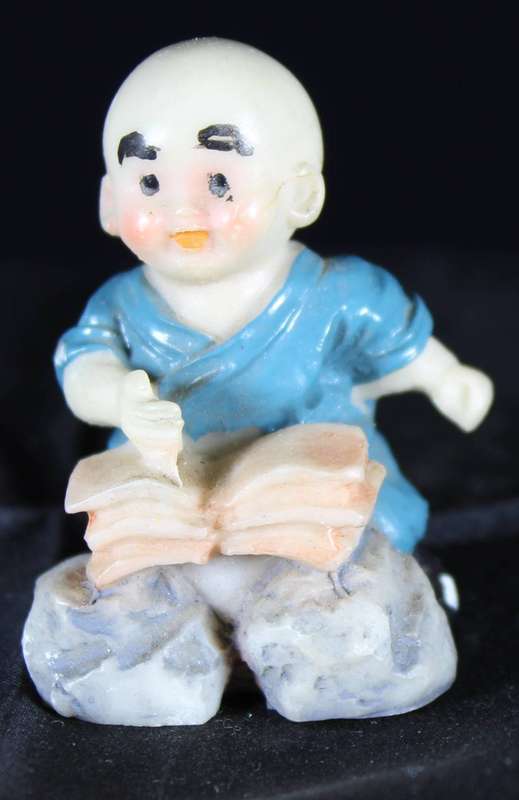 Little monk sitting with book